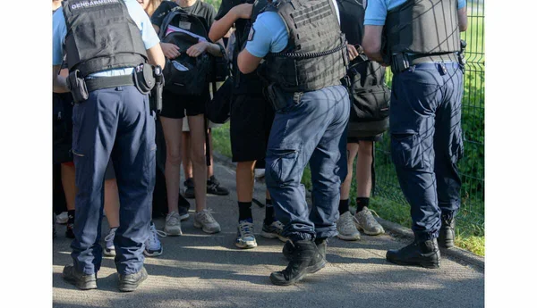 Trois gendarmes français en tenue d'interaction avec des civils sur la voie publique.