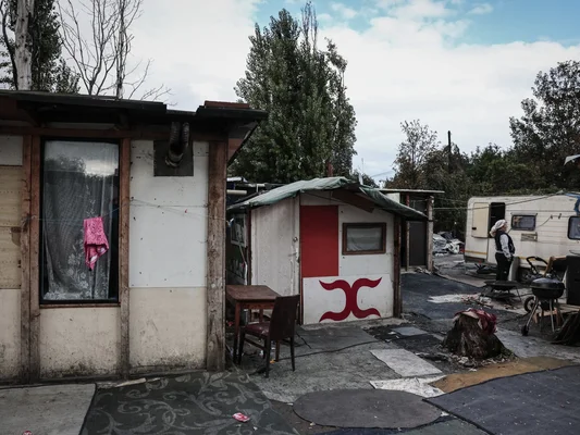 Habitant du bidonville de Stains près d'une caravane et d'abris précaires.