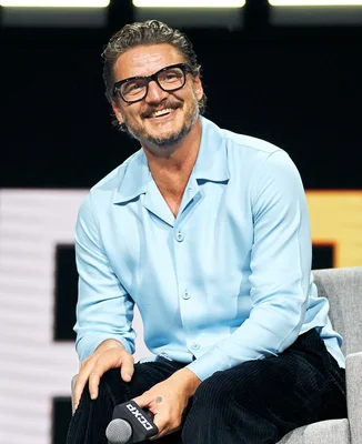 Pedro Pascal souriant lors d'une interview, vêtu d'une chemise bleu clair.