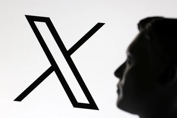 Silhouette d'un homme face à un écran géant arborant le logo X, symbole de la nouvelle identité du réseau social.