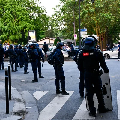 Policiers anti-émeute en position dans une rue, prêts à intervenir.