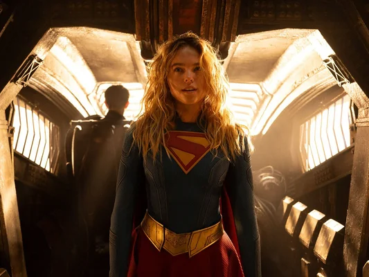 Milly Alcock en Supergirl dans un décor industriel sombre.