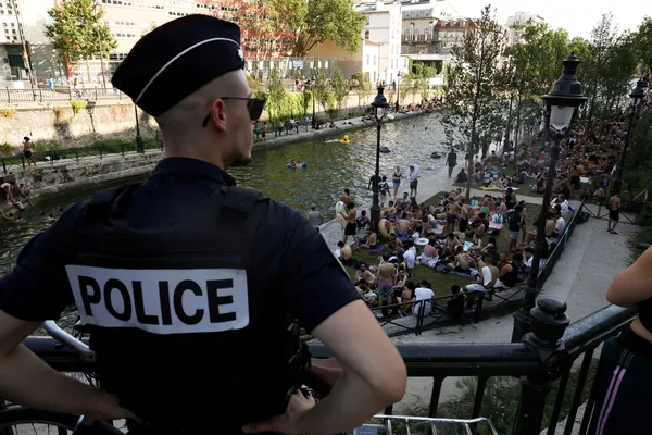 Un policier surveille les baigneurs sur les berges du Canal Saint-Martin à Paris.