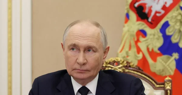 Vladimir Poutine dans un cadre officiel, les armoiries russes en arrière-plan.