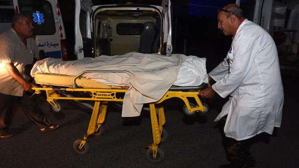Un brancard transportant un corps est conduit vers une ambulance lors d'une intervention de nuit.
