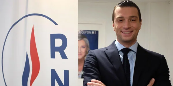Jordan Bardella, président du RN, devant un logo du parti.