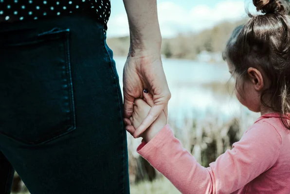 Main d’un adulte tenant celle d’un enfant, symbole de protection et de lien.