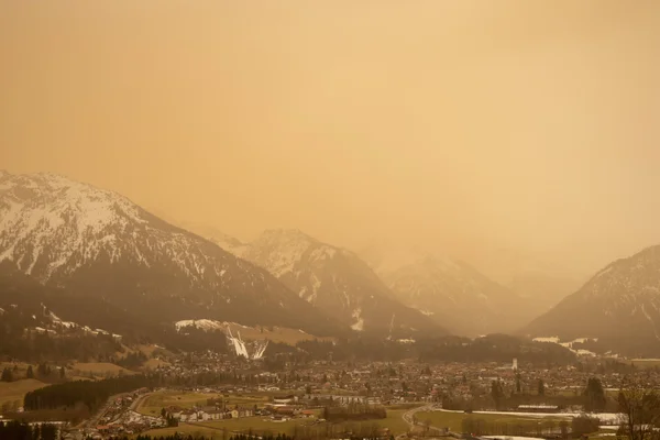 Poussières du Sahara en suspension dans l'atmosphère au-dessus d'une ville alpine.