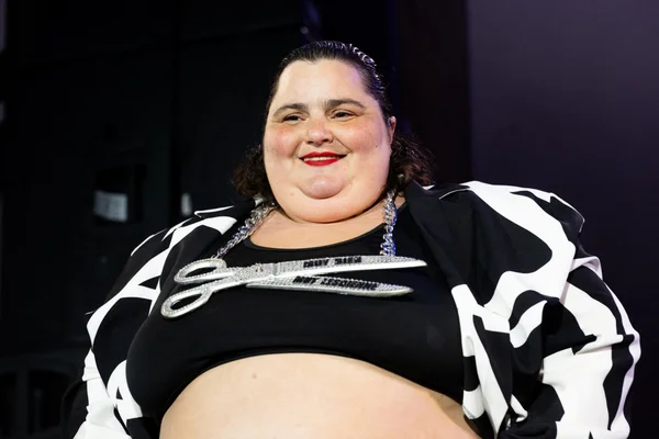 Barbara Butch, DJ, souriante dans une tenue scintillante.