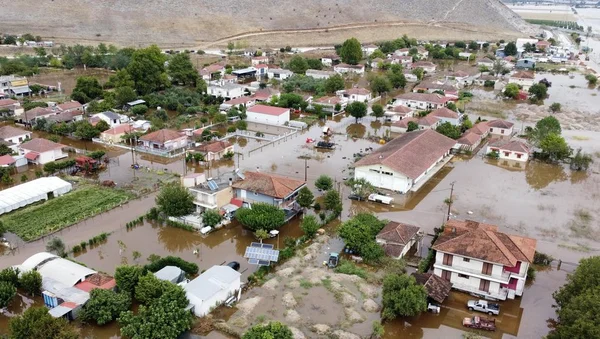 Village résidentiel submergé par des inondations boueuses, illustrant les dégâts climatiques extrêmes.