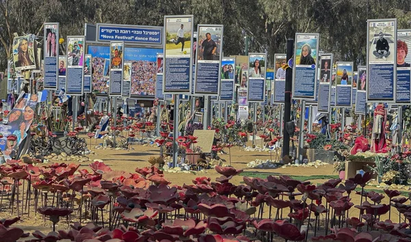 Mémorial en hommage aux victimes du 7 octobre, avec des panneaux de photos et des coquelicots rouges.