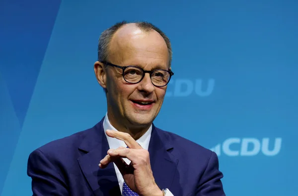 Friedrich Merz s'adressant à des interlocuteurs devant le logo de la CDU.