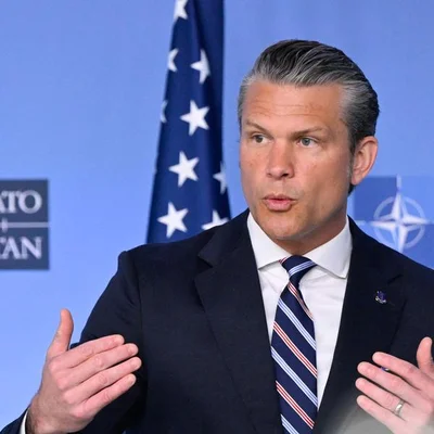 Un responsable s'adressant à la presse devant les symboles de l'OTAN et des États-Unis.
