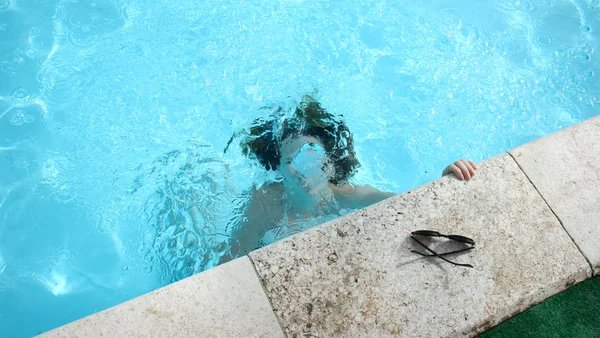 Personne immergée dans une piscine, s'accrochant au bord.