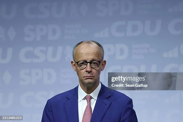 Friedrich Merz lors d'un événement politique, entouré des logos de partis allemands.