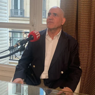 Daniel Siad interviewé par RTL, assis à une table en verre face à un micro.