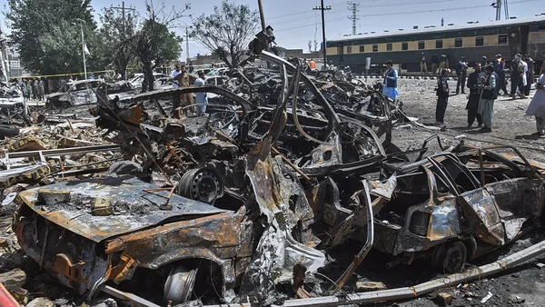 Conséquences de l'attaque à l'explosif d'un train au Pakistan : épave de véhicules et présence des secours.