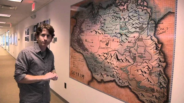Todd Howard dans les locaux de Bethesda Game Studios, devant une carte de Skyrim.