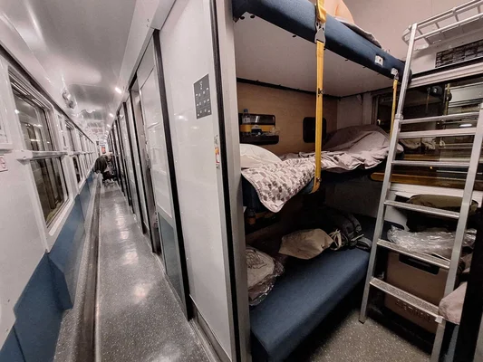 Intérieur d'un train de nuit, avec des couchettes et des compartiments pour les voyageurs.