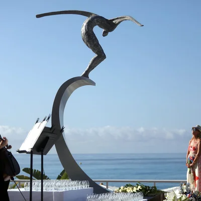 La statue du plongeur sur la Promenade des Anglais, avec une passante observant le paysage.