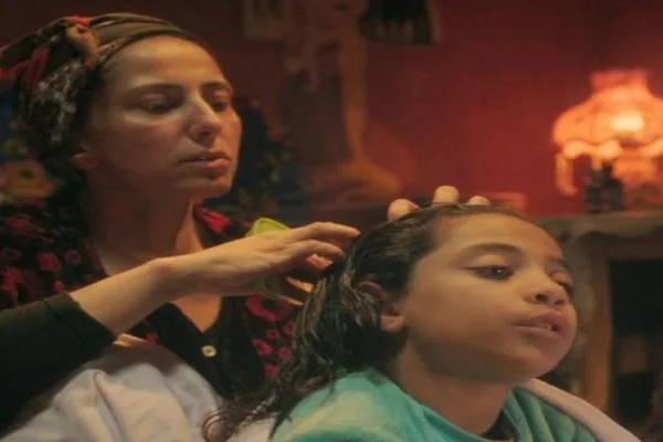 Scène du film « Happy Birthday » montrant une femme coiffant une jeune fille.