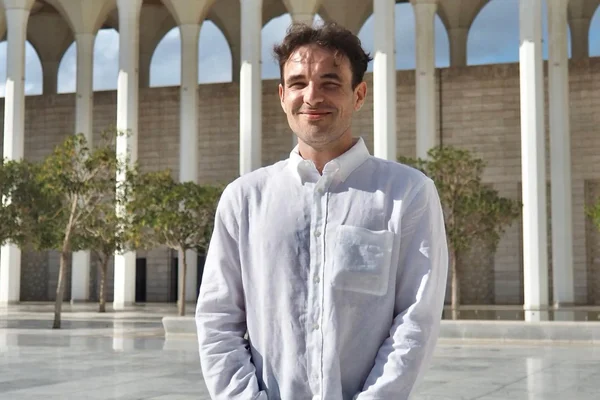 Christophe Gleizes souriant dans la cour d'un bâtiment à arches.