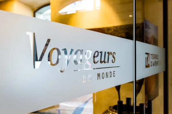 Enseigne en verre dépoli de Voyageurs du Monde et de sa filiale Terres d’Aventure.