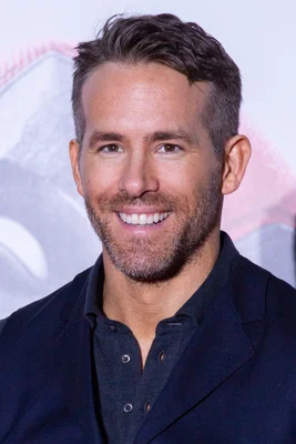 Ryan Reynolds souriant en blazer sombre lors d'un événement public.