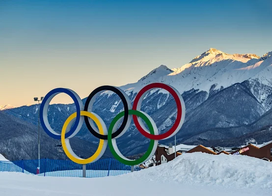 Anneaux olympiques sur fond de montagnes enneigées, symbolisant les Jeux d'hiver.