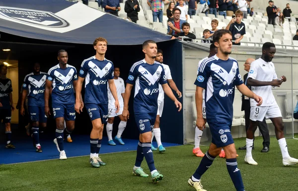 Les joueurs des Girondins de Bordeaux foulant la pelouse sous les yeux des supporters.