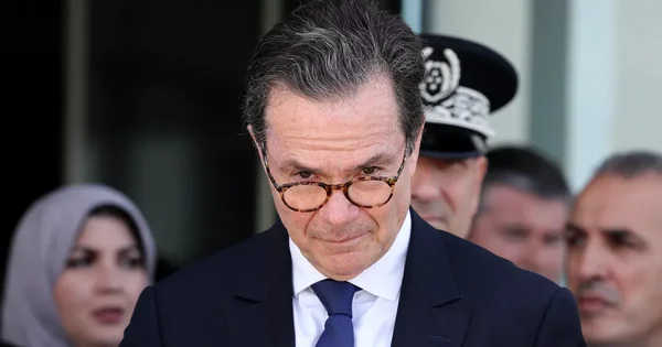 Personnalité non identifiée en costume, entourée de collaborateurs, lors d'une rencontre officielle.