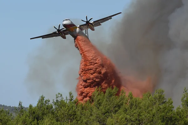 Avion bombardier d'eau larguant du retardant sur un incendie de forêt actif.
