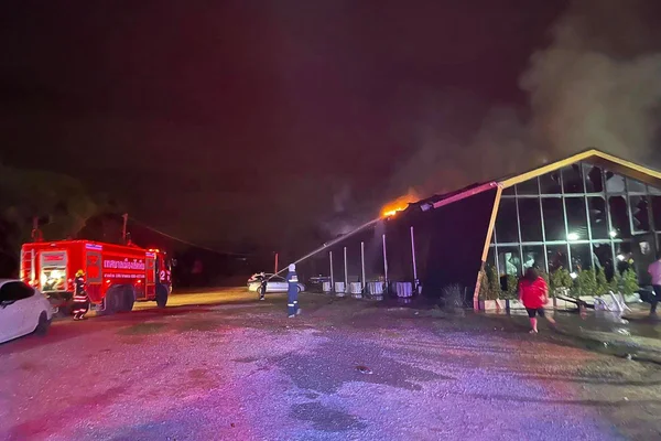 Intervention des pompiers lors de l'incendie d'une discothèque en Thaïlande, avec une épaisse fumée s'élevant du bâtiment.