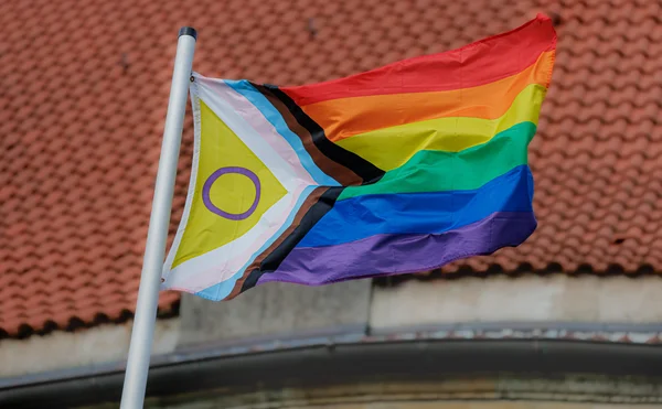 Drapeau Progress Pride flottant au vent, symbole de la diversité des genres.