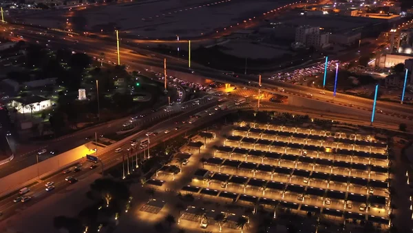 Vue aérienne nocturne de l'intersection de la rue Ras Abu Aboud et de la corniche à Doha, illustrant l'infrastructure routière qatarie.