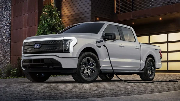 Ford F-150 Lightning blanc en recharge devant une maison moderne.