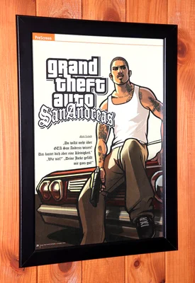 Photographie d'une page de magazine encadrée, montrant le protagoniste CJ assis sur une voiture dans une scène promotionnelle de Grand Theft Auto: San Andreas, avec du texte en allemand.