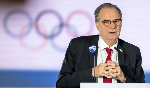 Renaud Muselier lors d'une conférence de presse, avec les anneaux olympiques en arrière-plan.