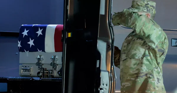 Un soldat américain saluant un cercueil drapé du drapeau des États-Unis lors d'une cérémonie de transfert digne.