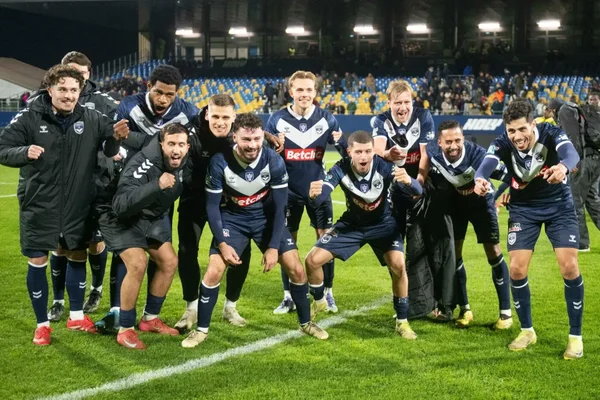 Joueurs des Girondins de Bordeaux en photo de groupe après une célébration nocturne.