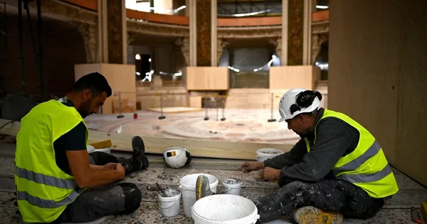 Travaux de rénovation au Palais de la découverte : des ouvriers dans le grand hall en chantier.