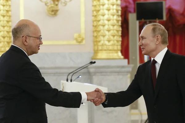 Poignée de main entre un responsable français et Vladimir Poutine dans un décor officiel.
