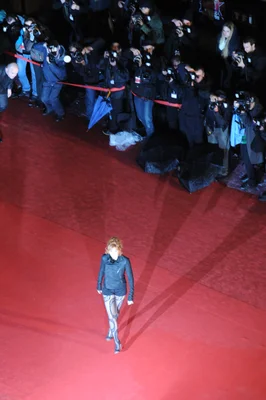 Mylène Farmer sur un tapis rouge, entourée de photographes.