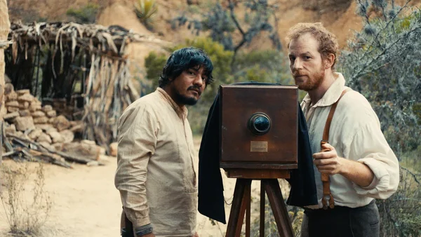 Scène de tournage de Vers la bataille montrant un photographe et son sujet dans un paysage aride.