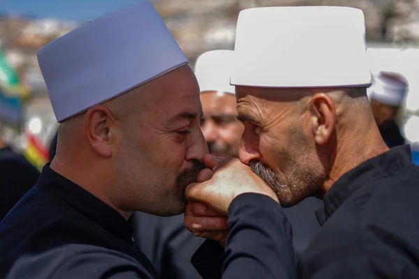 Geste de respect entre deux hommes druzes coiffés du fez blanc, lors d'une cérémonie en Syrie.