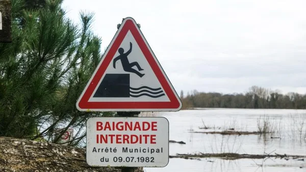 Panneaux 'Baignade Interdite' et de danger de plongeon au bord d'un plan d'eau.