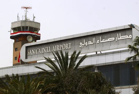 Aéroport international de Sanaa au Yémen, montrant sa façade avec le nom en anglais et en arabe et une tour de contrôle en arrière-plan, dans le contexte de fermeture après des raids saoudiens.