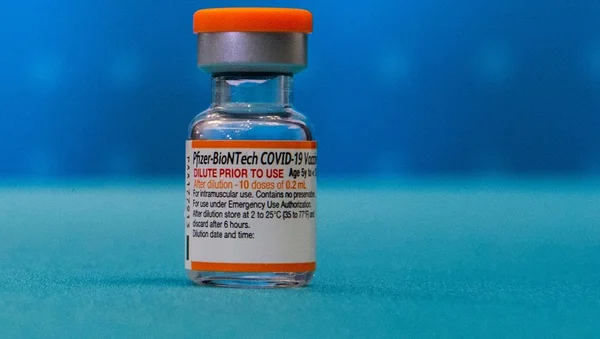 Annonce du lancement d'un vaccin combiné Covid-19 et grippe par Pfizer-BioNTech : gros plan sur un flacon du vaccin Pfizer-BioNTech COVID-19 à bouchon orange sur fond bleu.
