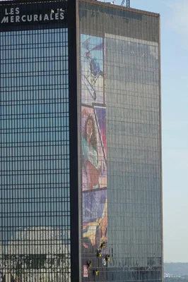 Tour des Mercuriales de Bagnolet avec une immense bannière colorée de la campagne GTA 6 en cours d'installation par des grimpeurs sur sa façade vitrée