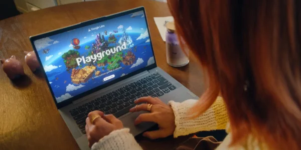Une personne aux cheveux roux utilisant un ordinateur portable affichant l'interface Google Labs Playground avec un monde de jeu coloré et flottant en île